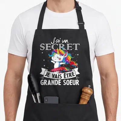 Tablier de cuisine noir avec licorne aux cheveux arc-en-ciel et texte J'ai un secret Je vais être grande soeur.