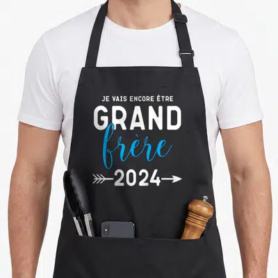 Tablier de cuisine noir avec inscription Je vais encore être grand frère 2024 en blanc et bleu.