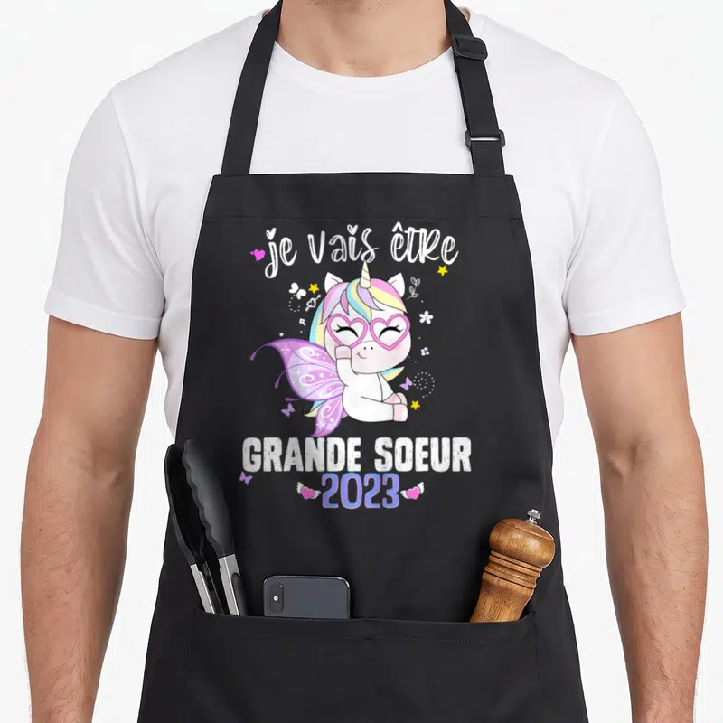 Tablier de cuisine noir avec une licorne rose et l'inscription je vais être grande sœur 2023.