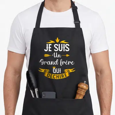 Tablier de cuisine noir avec inscription Je suis un grand frère qui déchire en blanc et jaune orné de couronnes et flèches.
