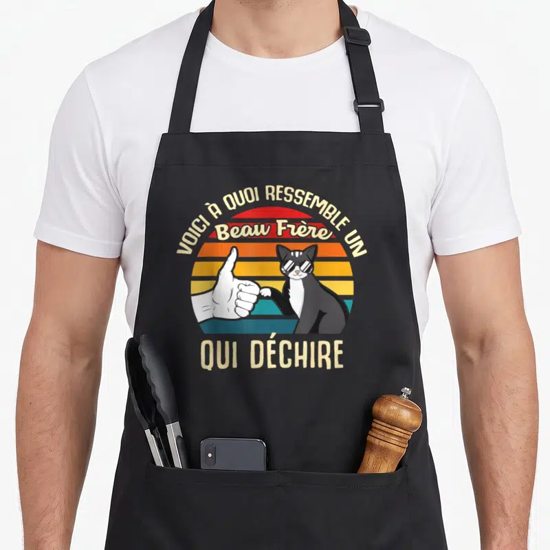 Tablier de cuisine noir avec illustration d'un chat en lunettes de soleil et une main faisant le pouce sur fond coloré rétro.