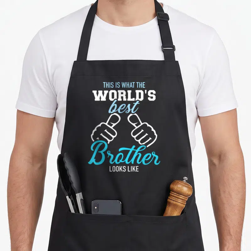 Tablier de cuisine noir avec inscription Voici à quoi ressemble le meilleur brother du monde et deux mains faisant des pouces levés.