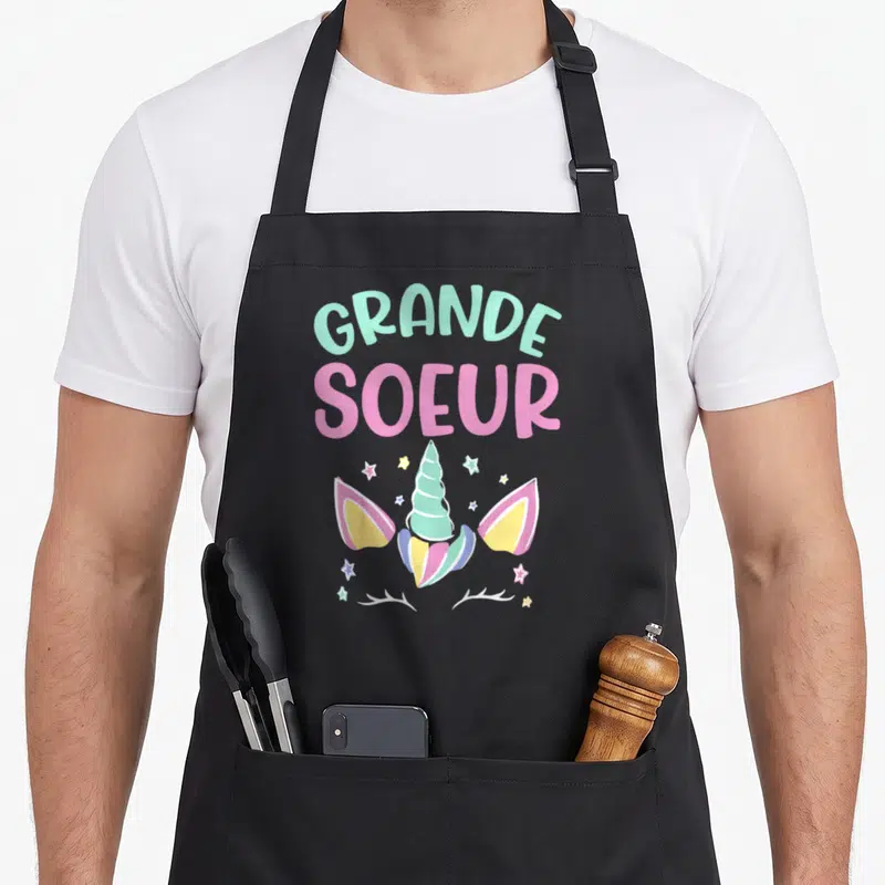 Tablier de cuisine noir avec inscription Grande Soeur et illustration de licorne pastel aux étoiles.