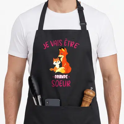 Tablier de cuisine noir avec deux renards et l'inscription Je vais être grande soeur en lettres roses.