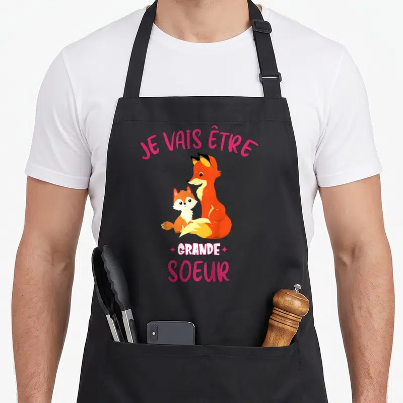 Tablier de cuisine noir avec deux renards et l'inscription Je vais être grande soeur en lettres roses.