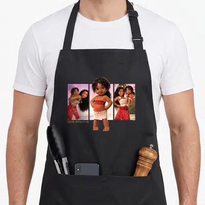 Tablier de cuisine noir avec Simea et Vaiana posant ensemble sur un fond de plage tropicale aux teintes roses et bleues.