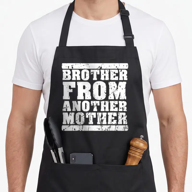 Tablier de cuisine noir avec l'inscription blanche « Brother from Another Mother Friendship » au style dégradé et texturé.
