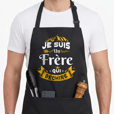 Tablier de cuisine noir avec inscription Je Suis Un Frère Qui Déchire en blanc et or surmonté d'une montagne stylisée.