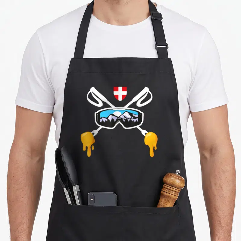 Tablier de cuisine noir avec raclettes croisées, lunettes de ski et drapeau suisse.