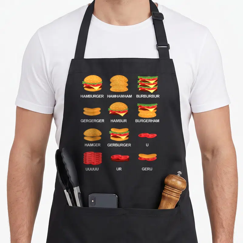 Tablier de cuisine noir avec des illustrations de burgers décomposés et des textes humoristiques comme Hamhamham ou Burburbur.