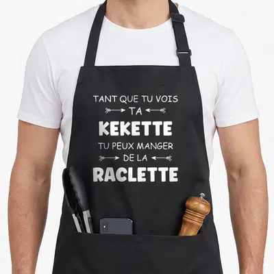 Tablier de cuisine noir avec inscription blanche humoristique sur le thème de la raclette et du fromage fondu.