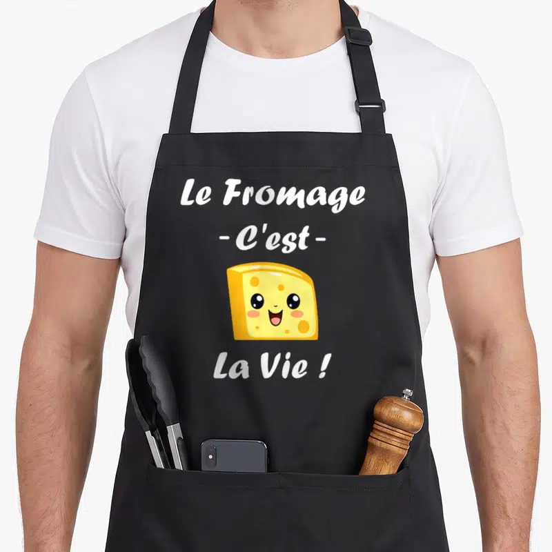 Tablier de cuisine noir avec un morceau de fromage jaune souriant et le texte Le Fromage Cest La Vie en blanc
