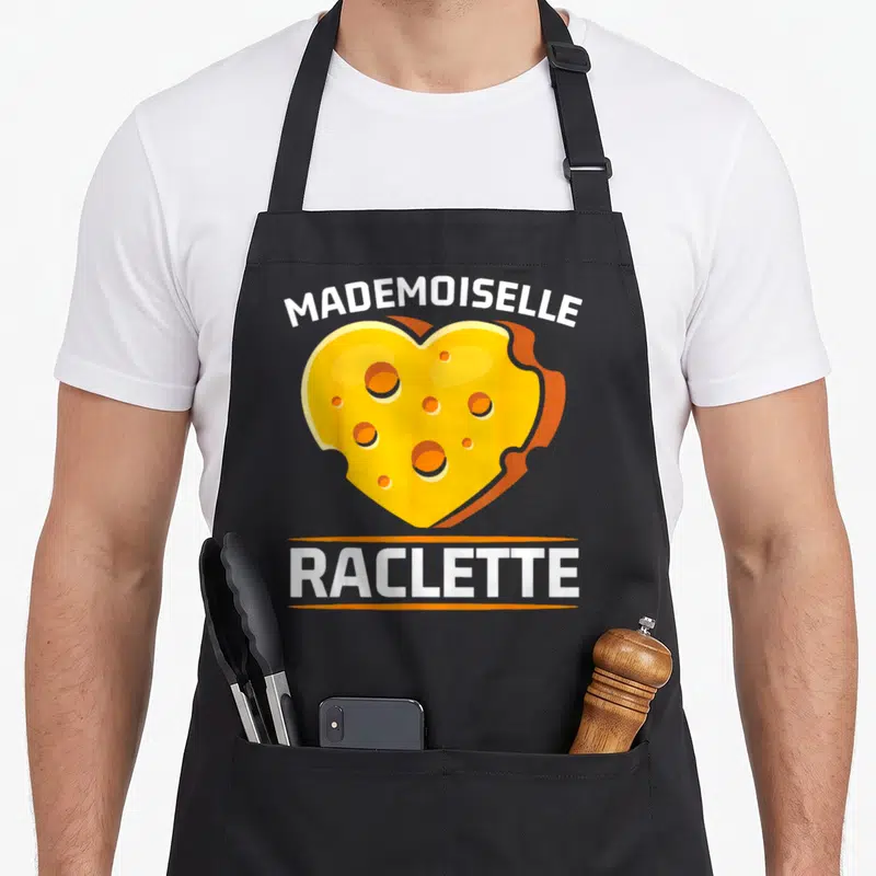 Tablier de cuisine noir avec un cœur en raclette jaune et le texte Mademoiselle Raclette imprimé en blanc.
