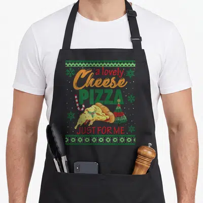 Tablier de cuisine noir avec une illustration de pizza au fromage, flocons de neige et texte festif coloré.