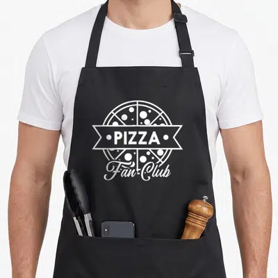 Tablier de cuisine noir avec logo Pizza Fan Club et illustration stylisée de pizza pepperoni en blanc.
