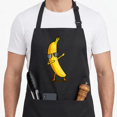 Tablier de cuisine noir avec une illustration de banane jaune portant des lunettes de soleil et faisant un mouvement de danse dab.