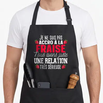 Tablier de cuisine noir avec inscription blanche et rouge sur la passion pour la fraise et quatre illustrations de baies.