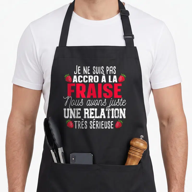Tablier de cuisine noir avec inscription blanche et rouge sur la passion pour la fraise et quatre illustrations de baies.