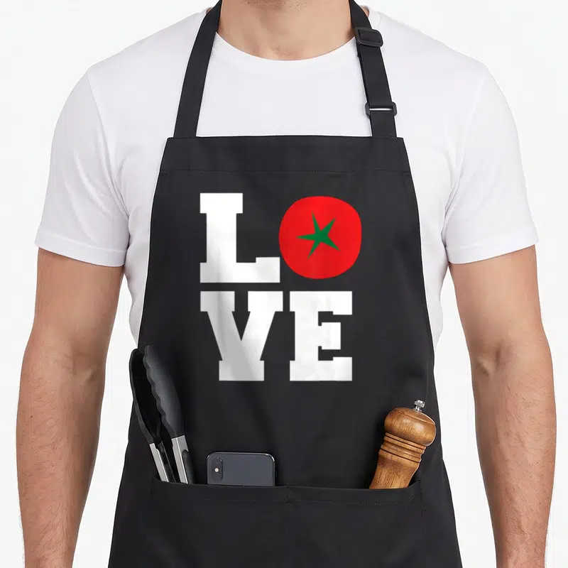 Tablier de cuisine noir avec l'inscription blanche LOVE et une tomate rouge remplaçant la lettre O