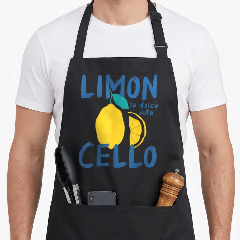 Tablier de cuisine noir avec illustration d'un citron jaune et du texte bleu Limoncello la dolce vita.