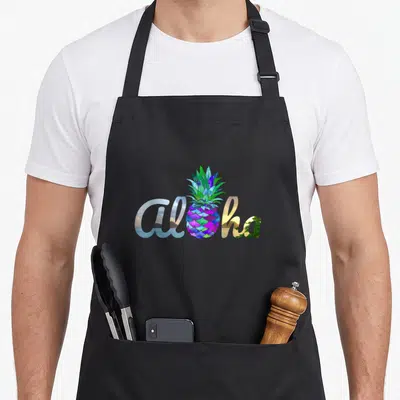 Tablier de cuisine noir avec un ananas violet et le mot Aloha aux motifs naturels.