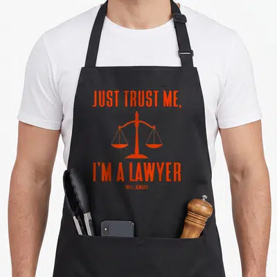Tablier de cuisine noir avec inscription orange Just Trust Me I'm a Lawyer Well Almost et une balance de la justice au centre.