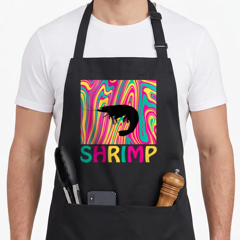 Tablier de cuisine noir avec silhouette de crevette sur fond ondulé multicolore et texte shrimp en bas.