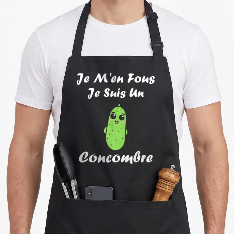 Tablier de cuisine noir avec un concombre vert souriant et le texte blanc Je m'en fous je suis un concombre.