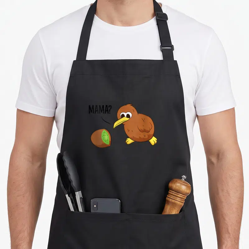 Tablier de cuisine noir avec illustration d'un oiseau kiwi regardant un fruit kiwi coupé avec la mention MAMA?