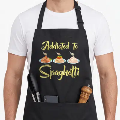 Tablier de cuisine noir avec trois assiettes de spaghetti et le texte Addicted To Spaghetti en lettres jaunes.