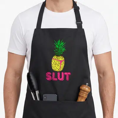 Tablier de cuisine noir avec un ananas jaune portant un string rose et le mot Slut en lettres roses.