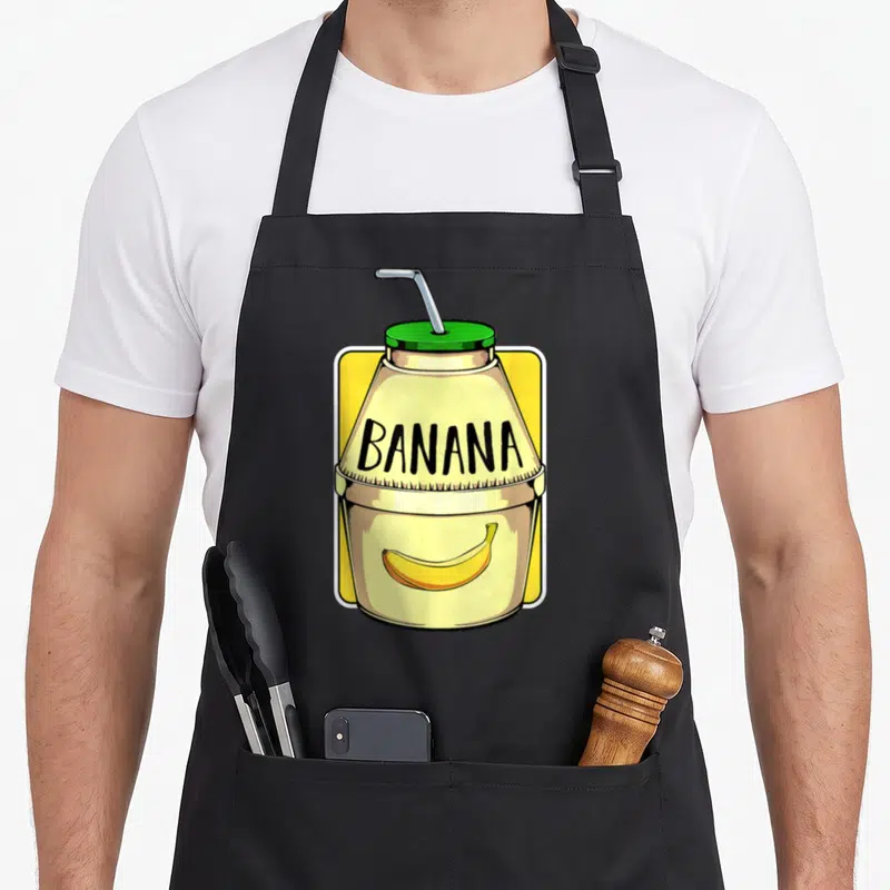 Tablier de cuisine noir avec illustration d'une bouteille de lait jaune portant l'inscription Banana et une banane dessinée.
