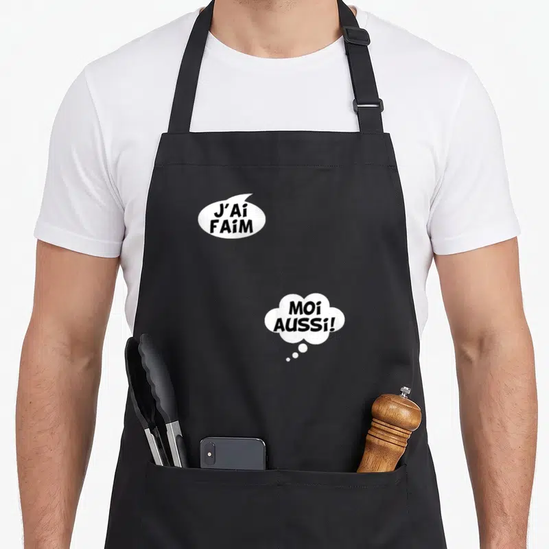 Tablier de cuisine noir avec deux bulles de dialogue blanches affichant J'ai faim et Moi aussi en lettres noires stylisées.
