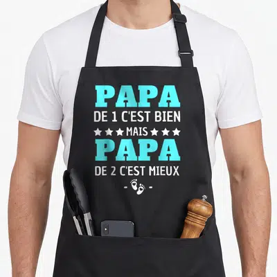 Tablier de cuisine noir avec texte Papa de 2 c'est mieux et deux petites empreintes de pieds blanches en bas du design.