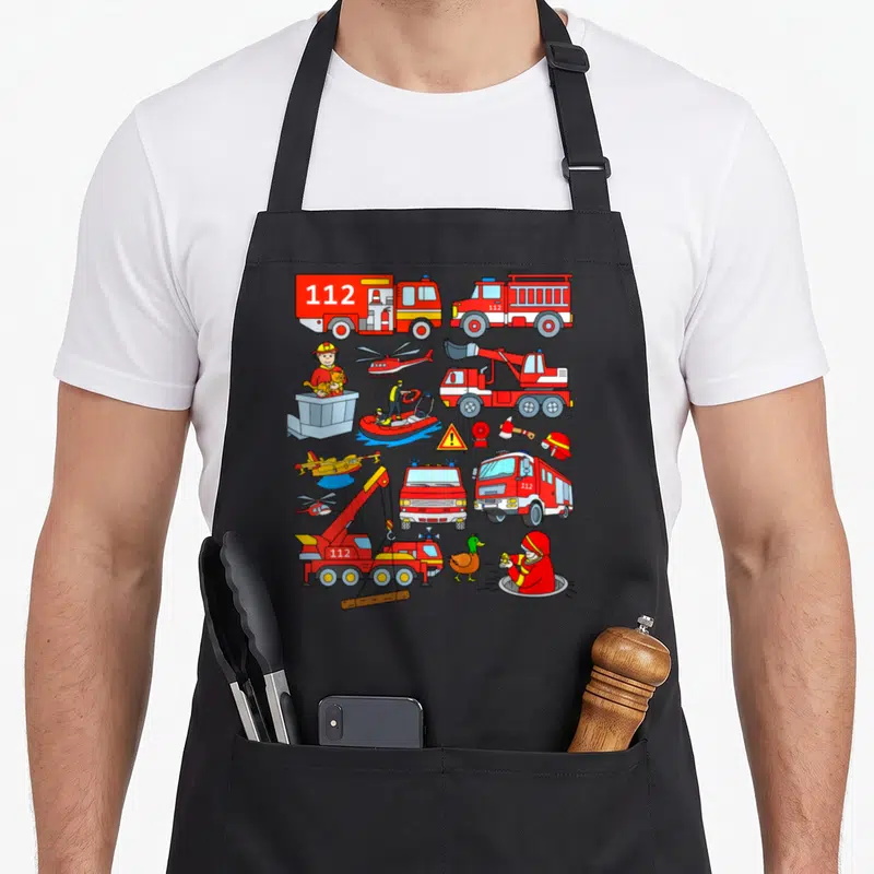 Tablier de cuisine noir avec illustrations colorées de pompiers, camions rouges 112, hélicoptères et bateaux de sauvetage.