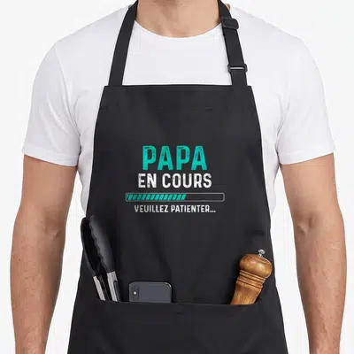 Tablier de cuisine noir avec l'inscription Papa en cours et une barre de progression turquoise.