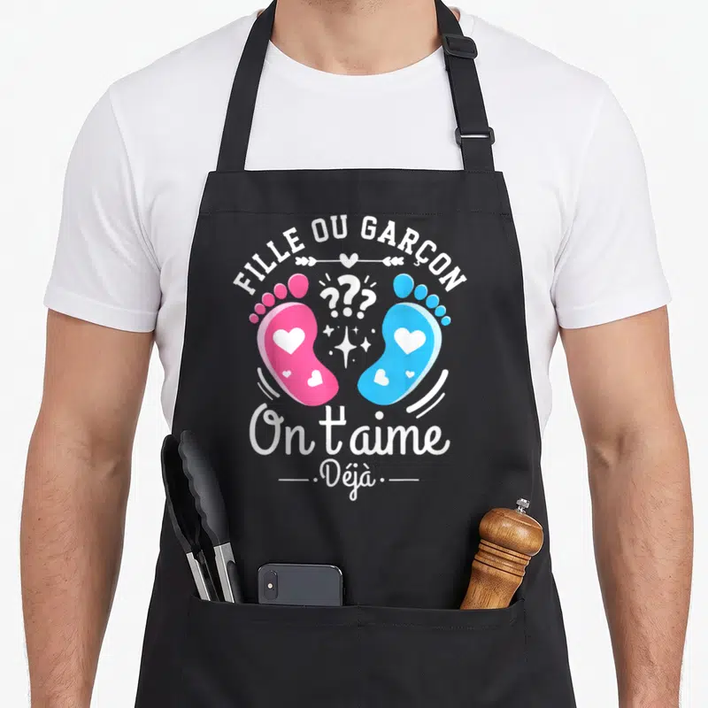 Tablier de cuisine noir avec l'inscription Fille ou Garçon et deux petits pieds roses et bleus ornés de cœurs.