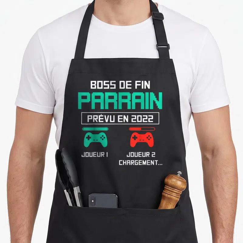 Tablier de cuisine noir avec texte Boss de fin Parrain et deux manettes de jeu vertes et rouges.