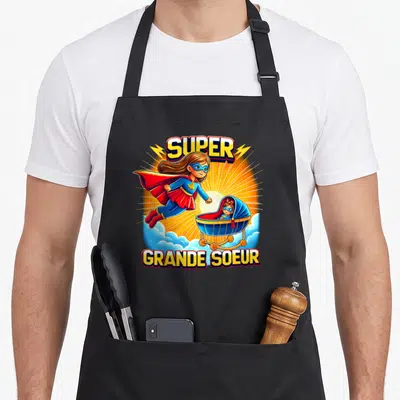Tablier de cuisine noir avec illustration colorée d'une super-héroïne et d'une poussette sur fond rayonnant.