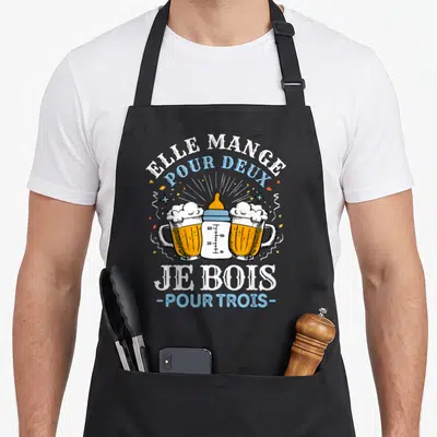 Tablier de cuisine noir avec l'illustration d'un biberon encadré par deux verres de bière et le texte elle mange pour deux je bois pour trois.