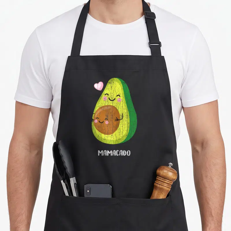 Tablier de cuisine noir avec un avocado souriant, un cœur rose et l'inscription Mamacado en bas.