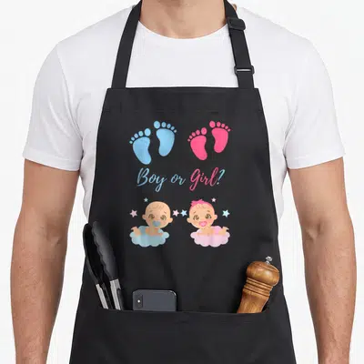 Tablier de cuisine noir avec prints de bébés sur nuages et texte Boy or Girl en bleu et rose.