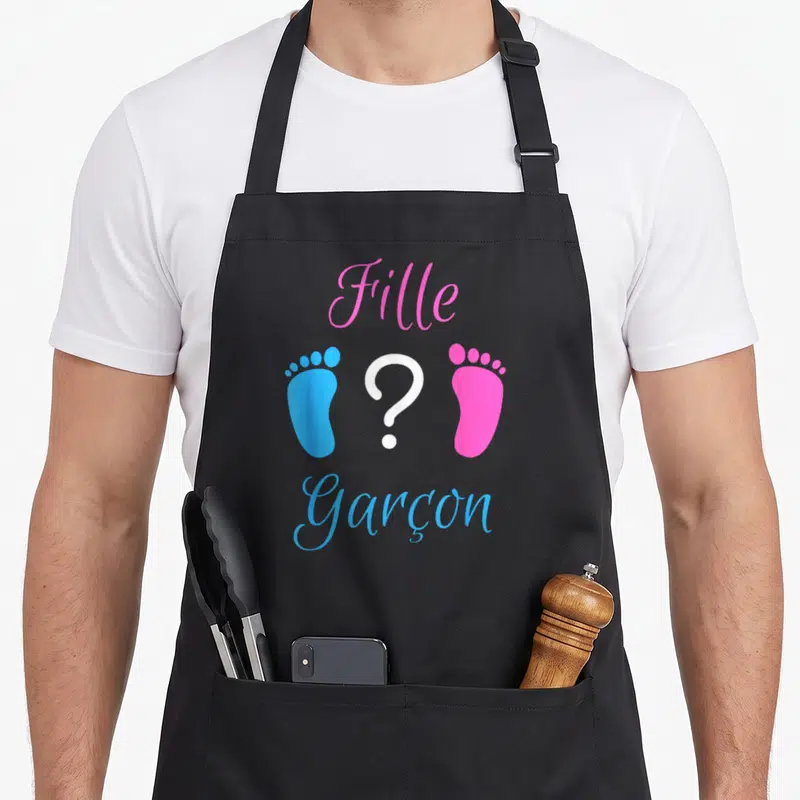 Tablier de cuisine noir avec l'inscription Fille et Garçon entourée d'empreintes de pieds colorées et d'un point d'interrogation central.