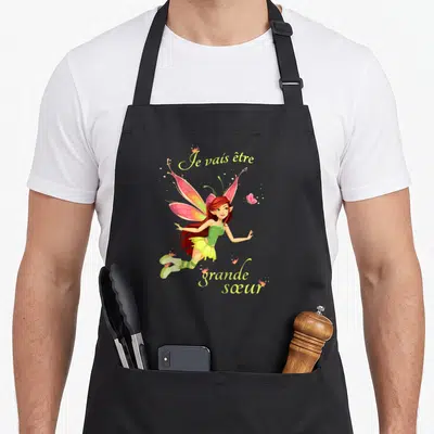 Tablier de cuisine noir avec une illustration de fée aux ailes roses et le texte Je vais être grande sœur 2027.