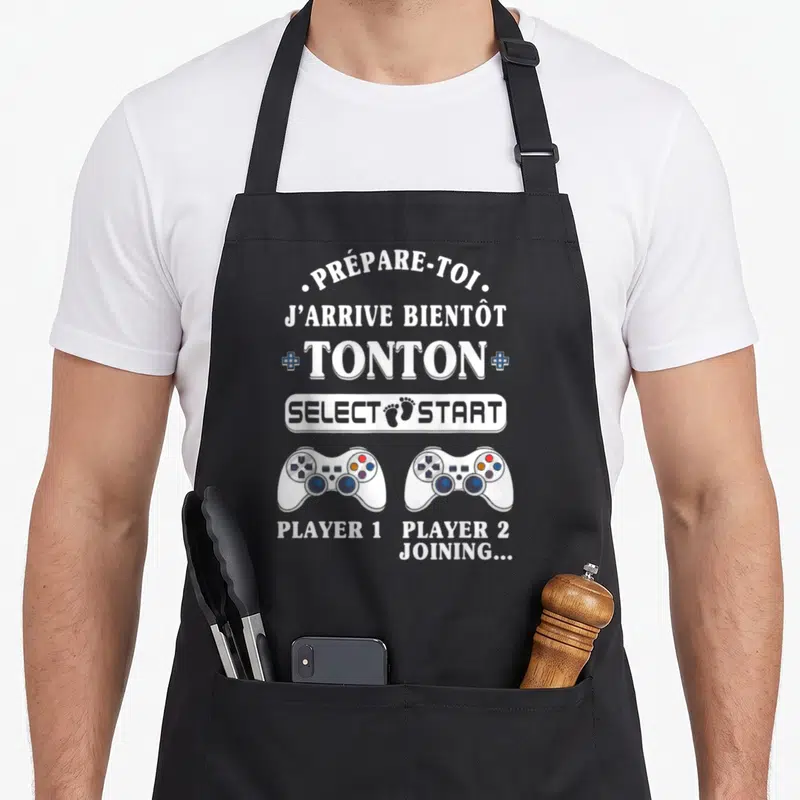 Tablier de cuisine noir avec message Prépare-toi Tonton et deux manettes de jeu vidéo Player 1 Player 2 joining.