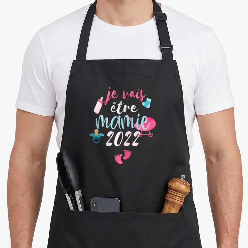 Tablier de cuisine noir avec le texte je vais être mamie 2022 entouré d'icônes de maternité colorées.