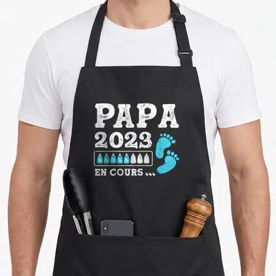 Tablier de cuisine noir avec inscription Papa 2023 En Cours et motifs de biberons bleus et blancs.