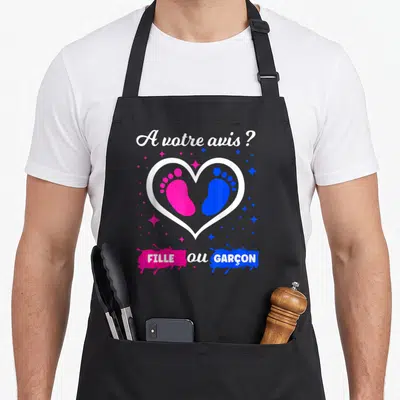 Tablier de cuisine noir avec un cœur blanc contenant des empreintes roses et bleues et le texte A votre avis Fille ou Garçon.