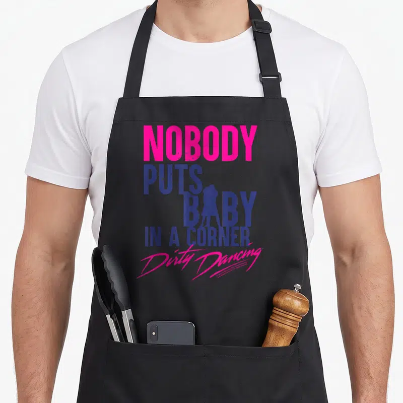 Tablier de cuisine noir avec l'inscription Nobody Puts Baby In A Corner et une silhouette de danseurs roses et bleues.