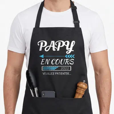 Tablier de cuisine noir avec l'inscription papy en cours 2022 et une barre de progression bleue.